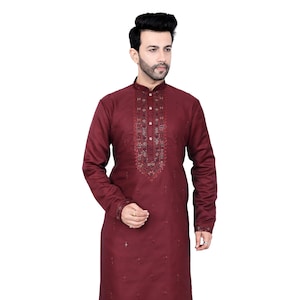 May include: A maroon long-sleeved kurta with intricate embroidery on the neckline and scattered throughout the fabric. The kurta is paired with white trousers and brown shoes.