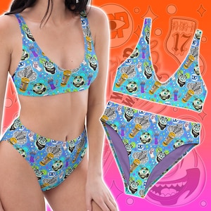 May include: A two-piece bikini set in a vibrant blue with a repeating pattern of cartoon characters, eyes, and other whimsical elements. The bikini top is a scoop neck style, and the bottoms are high-waisted. The set is displayed on a gradient background.