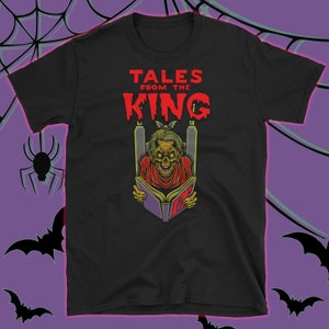 May include: Black t-shirt featuring a graphic of a zombie reading a book with the text "Tales from the King" in red.