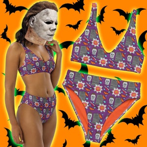 Może przedstawiać: Fioletowy i pomarańczowy bikini w stylu Halloween. Górna i dolna część bikini mają powtarzający się wzór nagrobka z napisem "SOUTHERN MYERS" i postacią w masce. Wzór zawiera również nietoperze, serca i kwiaty.