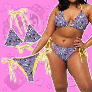 May include: A purple bikini set with a repeating pattern of sloths, drinks, and food items. The bikini top and bottom have yellow ties. The bikini is shown on a pink background.