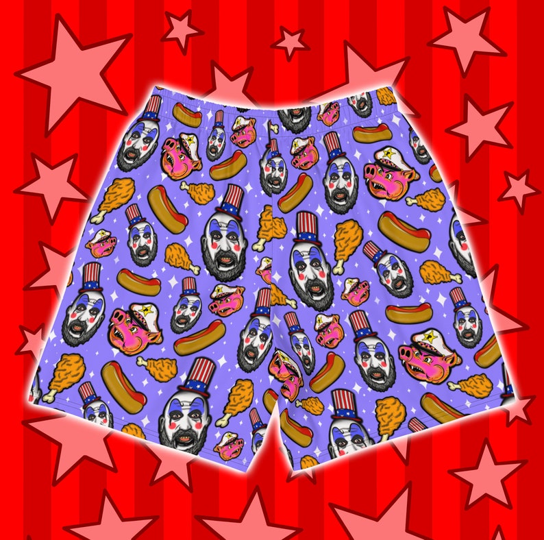 May include: Purple men's shorts with a repeating pattern of a clown wearing a red, white, and blue hat, a pig, a hot dog, and a fried chicken leg.