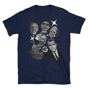 May include: Navy blue t-shirt featuring a collage of black and white illustrations of vintage horror and sci-fi characters. The design includes faces, an eye, and starbursts.