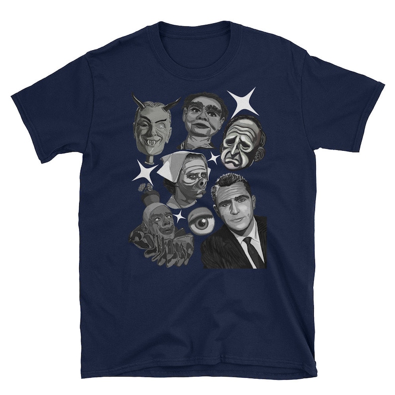May include: Navy blue t-shirt featuring a collage of black and white illustrations of vintage horror and sci-fi characters. The design includes faces, an eye, and starbursts.