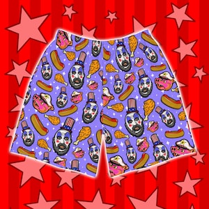 May include: Purple men's swim trunks with a repeating pattern of a man with a beard wearing a red, white, and blue hat, hot dogs, fried chicken, and pigs.