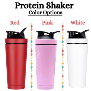 Puede incluir: Tres botellas de batido de prote&iacute;nas en rojo, rosa y blanco. Las botellas tienen tapas negras y una banda negra alrededor del medio.