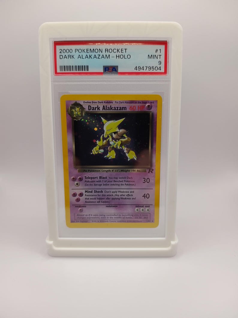 May include: A graded Pokemon card featuring Dark Alakazam from the Rocket set. The card is holographic and in mint condition. The card is graded a 9 by PSA and has a unique number 49479504.