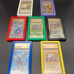 May include: Seven Pokemon trading cards in protective plastic cases. The cases are red, blue, green, yellow, white, black, and purple. The cards are graded with a number and a letter. The cards feature different Pokemon characters, including Electrode, Arbok, and Blastoise.