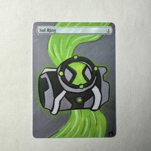 May include: A hand-painted card with a black, grey, and white device with a green circular emblem. The card has the text "Sol Ring" at the top, with a green, wavy design element. The background is grey.