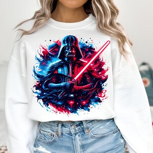 May include: White sweatshirt with a graphic print of Darth Vader holding a lightsaber in front of a galaxy background with red and blue colors.