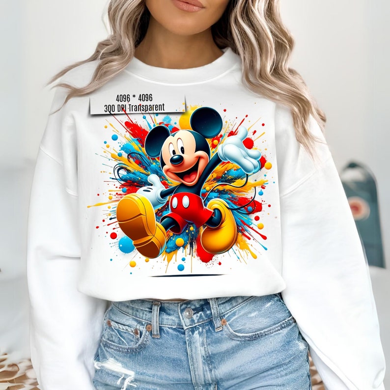 May include: White sweatshirt with a colorful graphic of Mickey Mouse in a red and yellow outfit, surrounded by colorful paint splatters.