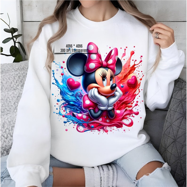 May include: White sweatshirt with a colorful graphic print of Minnie Mouse with a red bow and polka dots. The graphic features blue and red paint splatters and hearts.
