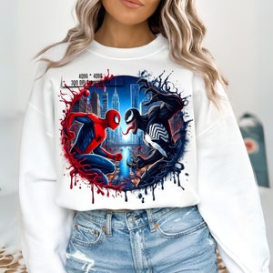 May include: White sweatshirt with a graphic print of Spider-Man and Venom fighting in a city setting. The graphic is surrounded by red and black paint splatters.