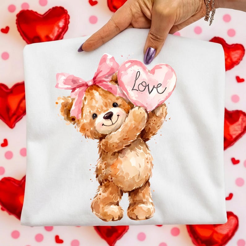 May include: White fabric featuring a watercolor illustration of a teddy bear holding a pink heart with the word "Love." The bear has a pink bow and is surrounded by red heart-shaped balloons and pink polka dots.