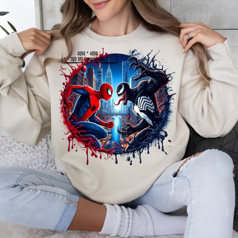 May include: A white sweatshirt with a graphic print of Spider-Man and Venom facing each other in a city setting. The graphic is surrounded by red and black paint splatters.