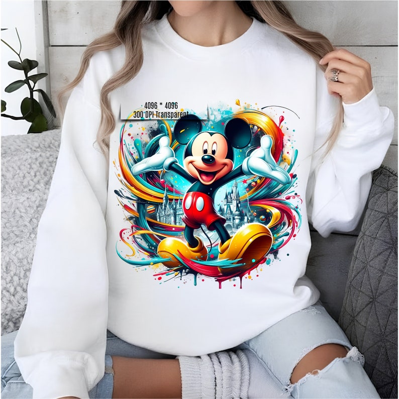 May include: White sweatshirt with a colorful graphic of Mickey Mouse in front of a castle. The graphic includes splashes of paint and colorful lines. The text "4096 x 4096 300 DPI Transparent" is printed on the sweatshirt.