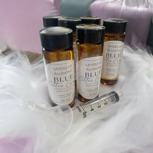 May include: Six small brown glass bottles with black lids and labels that read "Layerz of Illusions Blue Cotton Candy Diffuser Oil 30 ml".
