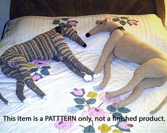 Puede incluir: Un patrón de crochet para dos galgos. Los perros están tumbados en una colcha blanca con un patrón floral. El texto "This item is a PATTERN only, not a finished product." está en la parte inferior de la imagen.