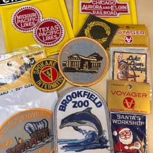 May include: A collection of embroidered patches, including those for the Missouri Pacific Lines, Texas Pacific Lines, Chicago Aurora and Elgin Railroad, and Brookfield Zoo. The patches feature various designs and text.