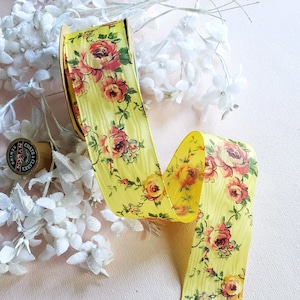 Può includere: Nastro di raso giallo con stampa floreale con rose rosa e arancioni. Il nastro è arrotolato su un rotolo.