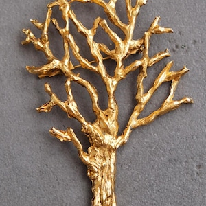 Könnte beinhalten: Eine goldfarbene Brosche aus Metall in Form eines Baumes mit filigranen Ästen.
