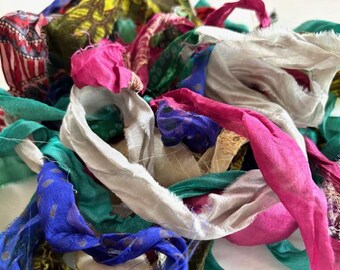 Könnte beinhalten: Nahaufnahme eines Haufens bunter Stoffreste. Die Reste sind in den Farbtönen Rosa, Blau, Grün, Weiß und gemusterten Stoffen gehalten. Der Stoff scheint Seide oder ein ähnliches leichtes Material zu sein.