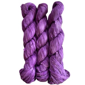 May include: Three skeins of purple silk ribbon, twisted together. The ribbon is made of thin, shredded silk and has a soft, textured look.
