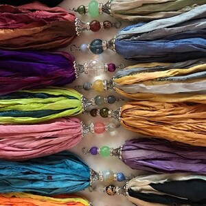 Puede incluir: Una colecci&oacute;n de borlas de cinta de seda coloridas con detalles de cuentas decorativas. Las borlas son de varios colores, incluyendo negro, rosa, morado, azul y naranja. Cada borla tiene una tapa de metal plateado y est&aacute; adornada con una variedad de cuentas.