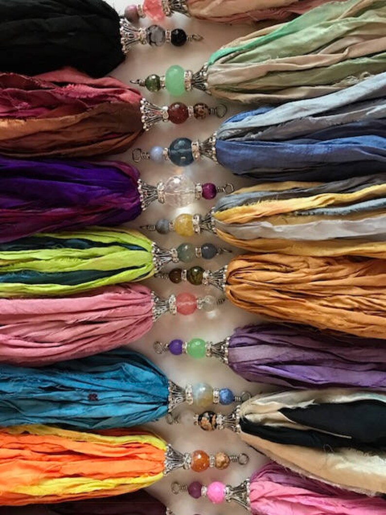 Puede incluir: Una colecci&oacute;n de borlas de cinta de seda coloridas con detalles de cuentas decorativas. Las borlas son de varios colores, incluyendo negro, rosa, morado, azul y naranja. Cada borla tiene una tapa de metal plateado y est&aacute; adornada con una variedad de cuentas.