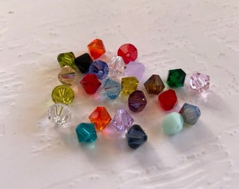 May include: Assortment of colorful glass beads in various shapes and sizes. The beads are clear, green, red, blue, purple, and yellow.