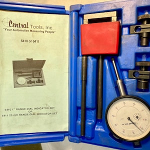 May include: A blue plastic case containing automotive measuring tools. The case is open, revealing a dial indicator, various rods, and a red block. Text on the inside reads "Central Tools, Inc." and "6410 or 6411".