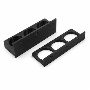 May include: Two black, rectangular holders, each with three circular openings. The holders have a flat back and a raised edge on each end. The holders are made of a matte black material and are designed to hold small cylindrical objects.