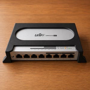 May include: A black and silver UniFi Switch 8 60W network device featuring eight Ethernet ports, status indicator lights for PoE and link activity, and a central oval panel with the brand name and model printed in black text on a silver background.