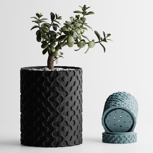 May include: A black, textured cylindrical planter with a small green plant. Beside it, a matching teal-colored planter with a similar pattern. The planters are designed for indoor or outdoor use.