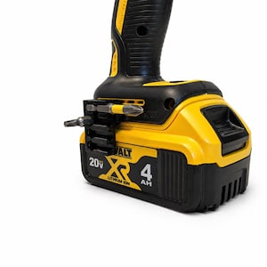 May include: A yellow and black DeWalt 20V Max Lithium Ion 4Ah battery pack attached to a power tool handle. A black plastic bit holder is mounted to the side of the battery, holding two metal screwdriver bits with yellow and silver accents.