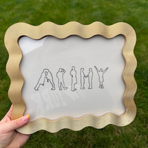 Puede incluir: Un marco de fotos rectangular con un borde dorado ondulado y texturizado. Dentro del marco, un fondo blanco presenta una ilustraci&oacute;n de l&iacute;neas negras de siete figuras dispuestas para deletrear la palabra ARMY, formando cada una una letra.