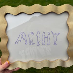 Puede incluir: Un marco rectangular con un borde ondulado y texturizado de color dorado que rodea una pantalla transparente. La pantalla presenta un gr&aacute;fico de l&iacute;neas moradas que deletrea la palabra ARMY, donde cada letra es la silueta de una persona.