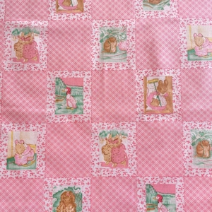 May include: A pink and white patchwork quilt with a repeating pattern of squares. Each square features a different illustration of animals in a storybook style. The quilt has a floral border and a gingham pattern.