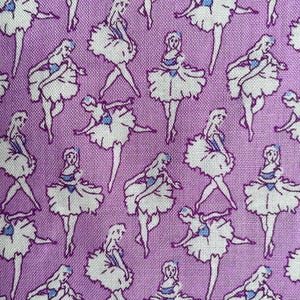 May include: Purple fabric with a repeating pattern of white ballerina figures. The ballerinas are wearing white tutus and have blue accents.