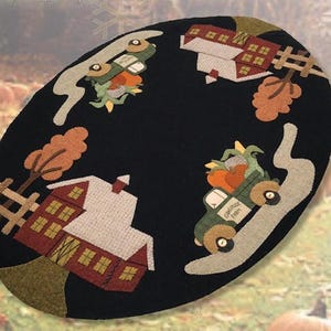 May include: Oval black rug with a fall harvest theme. Features a green truck carrying pumpkins, a red barn, and autumn leaves. The rug has a decorative fence and a road design.