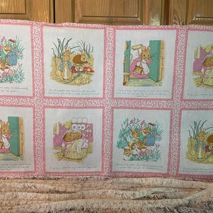 May include: A vintage fabric panel featuring eight illustrated scenes with rabbits and other animals in a garden setting. Each scene is framed with a pink floral border and includes text. The illustrations are in soft pastel colors.