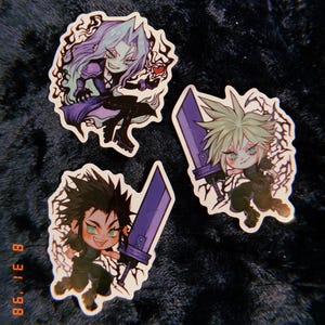 May include: Three cartoon stickers featuring characters from the Final Fantasy VII video game. The stickers are on a dark gray fuzzy surface. The characters are Cloud, Sephiroth, and Tifa. Each character is holding a sword and has a menacing expression.