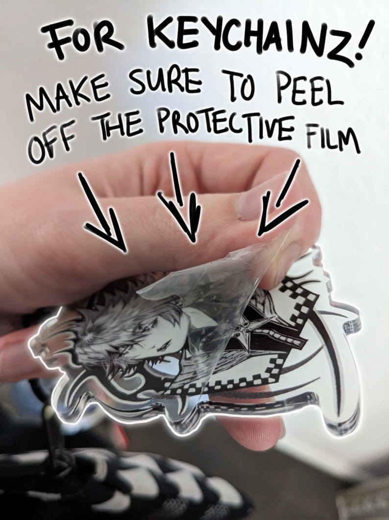 May include: A clear acrylic keychain featuring a black and white illustration of a character with spiky hair and a sword. The protective film is being peeled off the keychain. The text "FOR KEYCHAINZ! MAKE SURE TO PEEL OFF THE PROTECTIVE FILM" is written in black marker on a white background.