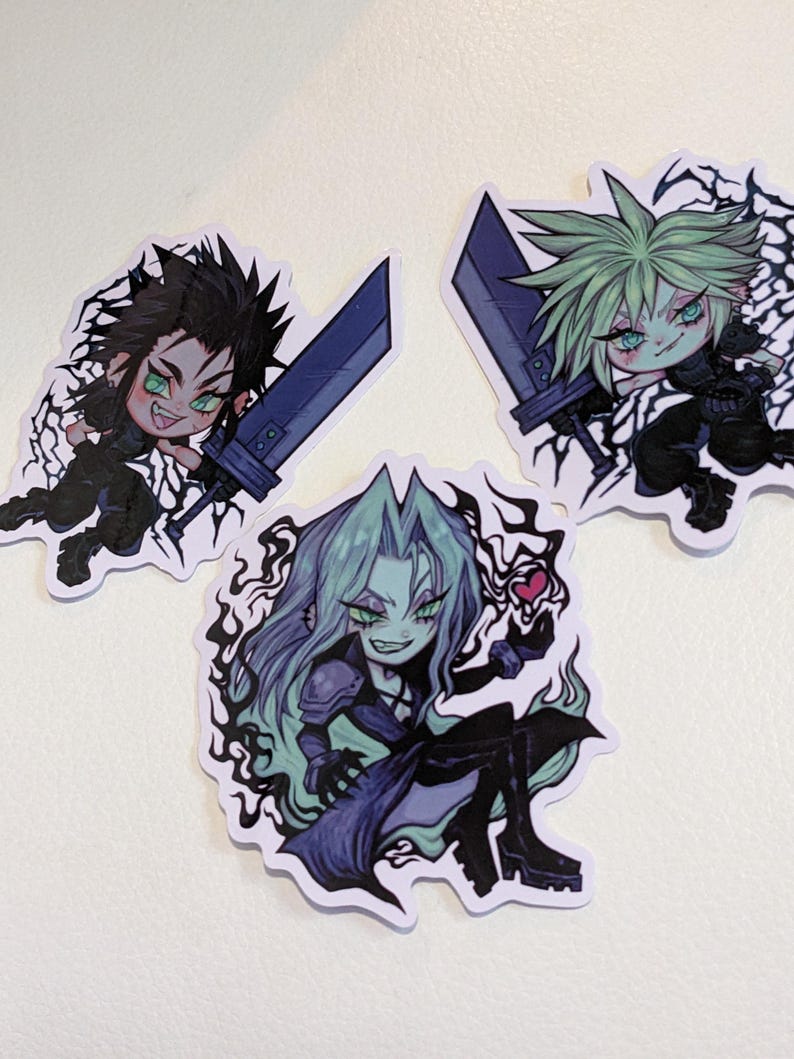 May include: Three cartoon stickers featuring characters from the Final Fantasy VII video game. The stickers are printed on white paper with black outlines. The characters are Cloud, Sephiroth, and Aerith. Cloud is holding a sword and has spiky blonde hair. Sephiroth has long black hair and is holding a sword. Aerith has long green hair and is holding a flower.