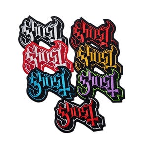 May include: Eight embroidered patches with the word "Ghost" in different colors, including white, red, yellow, blue, purple, and green. The patches are all in the same style, with a gothic font and a cross.