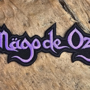 May include: Purple embroidered patch with the text "Magode Oz" on a black background.