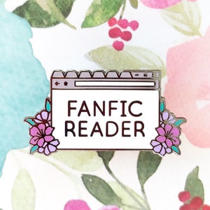 May include: A silver enamel pin featuring a white background with the text "FANFIC READER" inside a blue browser window. The browser window is decorated with two purple flowers on either side.