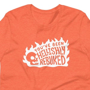 May include: Orange t-shirt with a white graphic of a skull in flames and the text "You've Been Hellishly Rebuked."