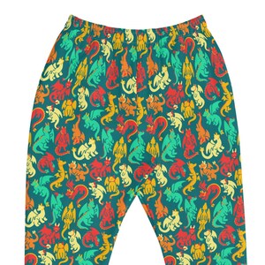 May include: Teal joggers with a repeating pattern of colorful dragons in red, yellow, orange, and green. The joggers have a fitted ankle cuff in a matching teal color. The waistband is elasticized.