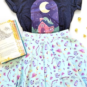 May include: A blue and white skirt with a whimsical pattern of teacups, swords, and flowers. The skirt is made of a lightweight fabric and has a flowy silhouette.